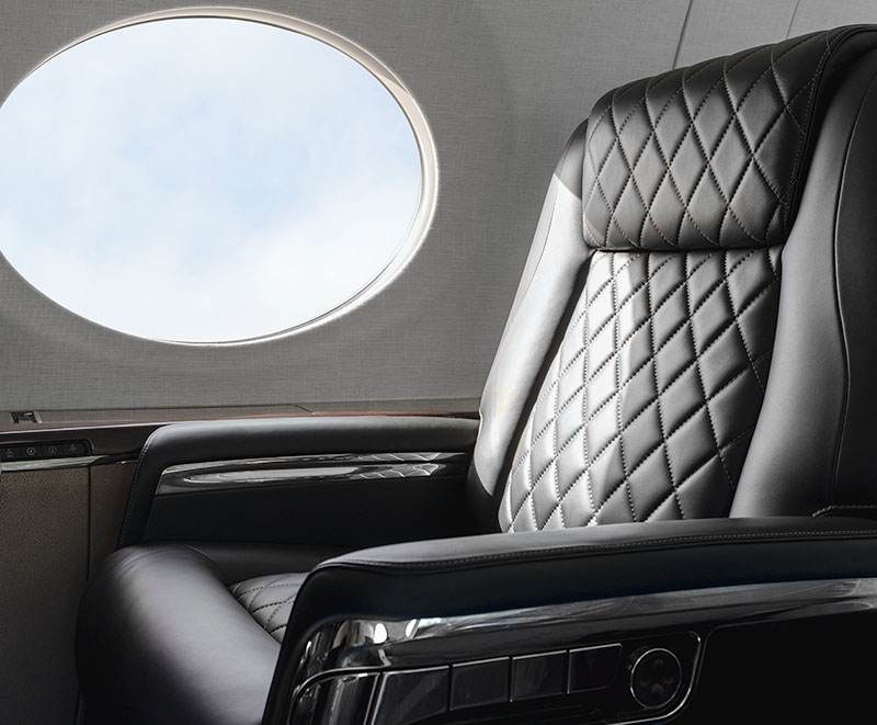 Black stitched leather seat on the starboard side of the fuselage with a view of large oval window