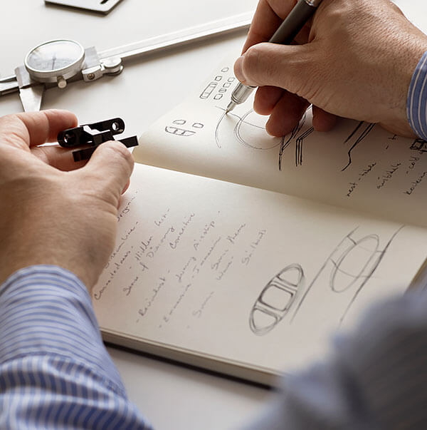 An engineer makes notes in a notebook filled with aircraft design elements.